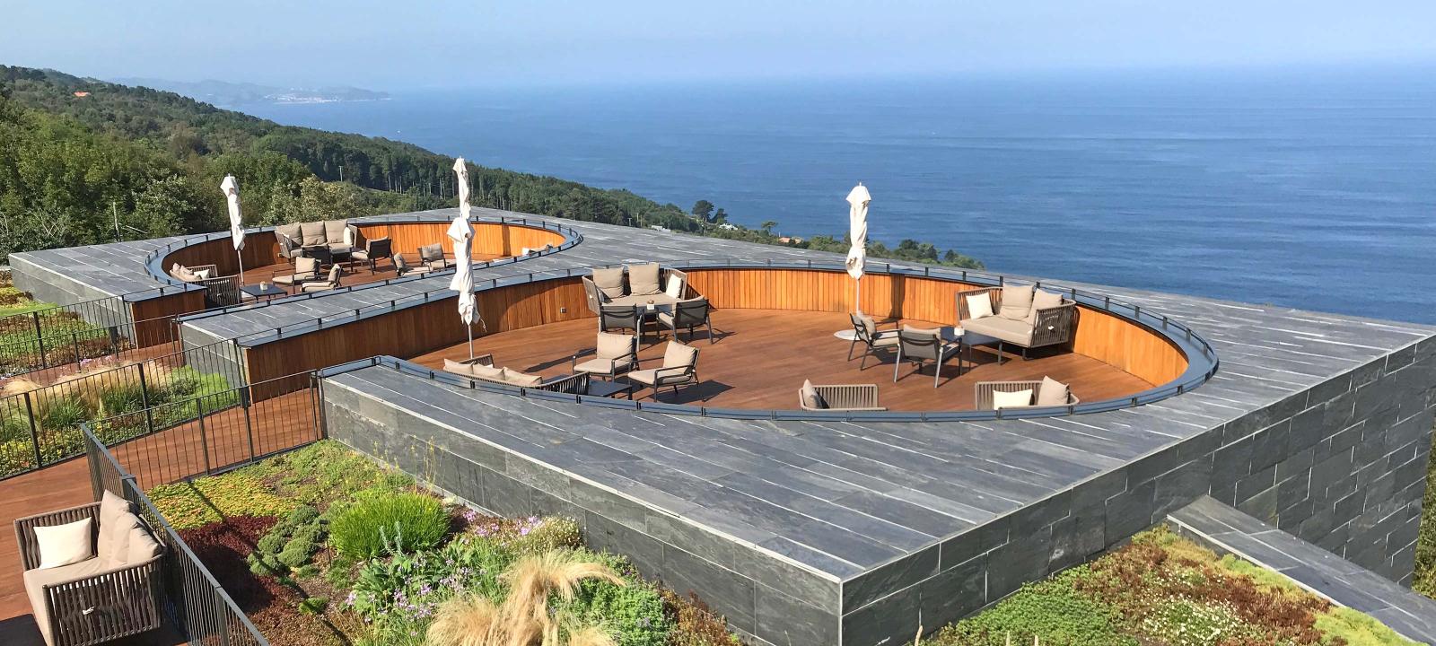 Terraces surrounded by vegetation and a view over the sea.